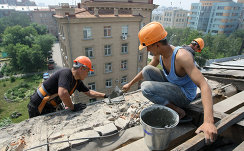 *Рабочие ремонтируют фасад и крышу жилого дома