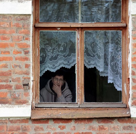 Женщина смотрит из окна своего дома в городе Чекалин Тульской области