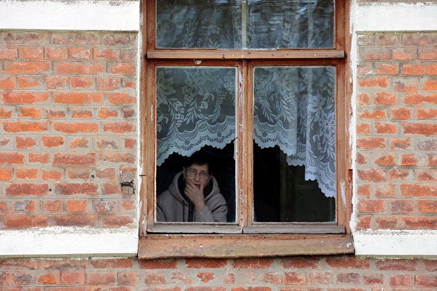 Женщина смотрит из окна своего дома в городе Чекалин Тульской области