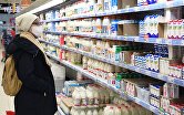 Покупательница выбирает товар в молочном отделе гипермаркета